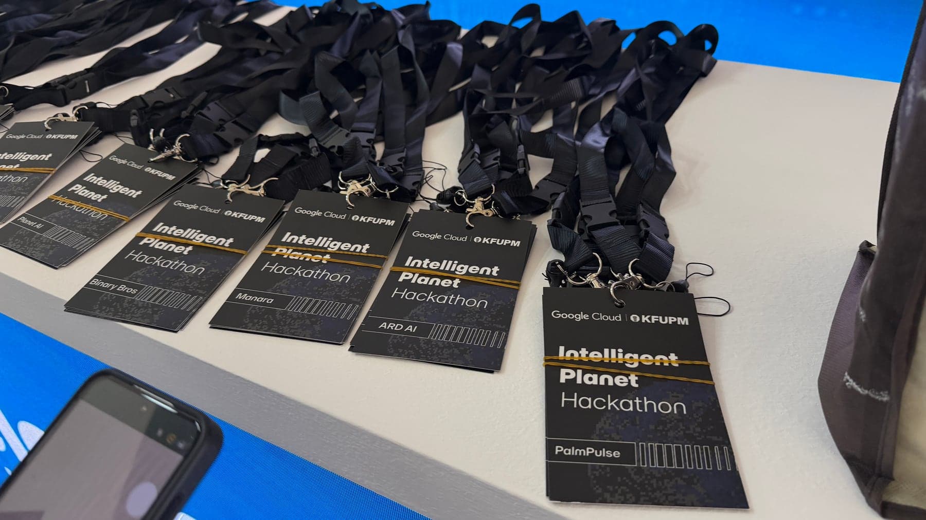 PalmPulse and other Intelligent Planet Hackathon badges on a registration table