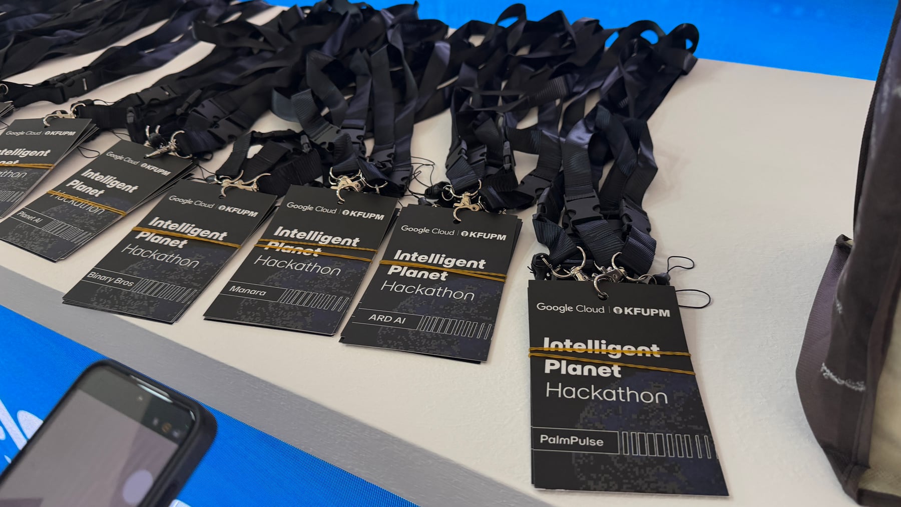 PalmPulse and other Intelligent Planet Hackathon badges on a registration table
